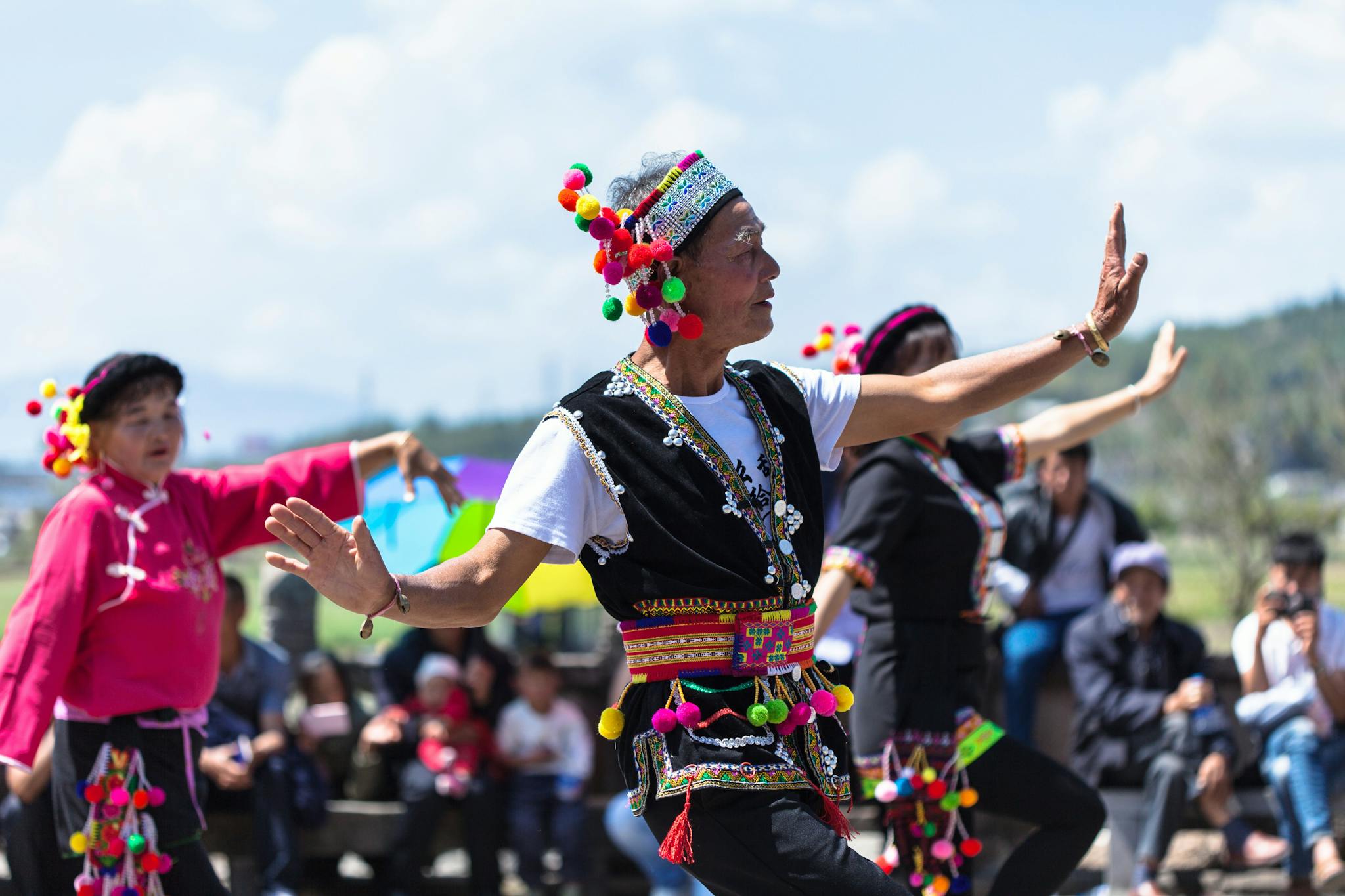 Vibrant outdoor traditional dance performance by adult dancers in colorful costumes.