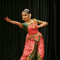 A skilled dancer performing Bharatanatyam in traditional attire on stage.