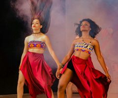 Dancers in colorful costumes perform energetically on a stage, embodying cultural expression and celebration.