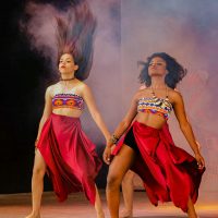 Dancers in colorful costumes perform energetically on a stage, embodying cultural expression and celebration.
