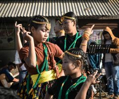Group of children performing traditional Asian dance outdoors.