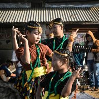 Group of children performing traditional Asian dance outdoors.