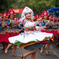 Joyful dancers in vibrant traditional costumes perform outdoors, creating a festive atmosphere.