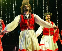Vibrant dance performance with traditional costumes on stage, capturing dynamic motion and cultural expression.